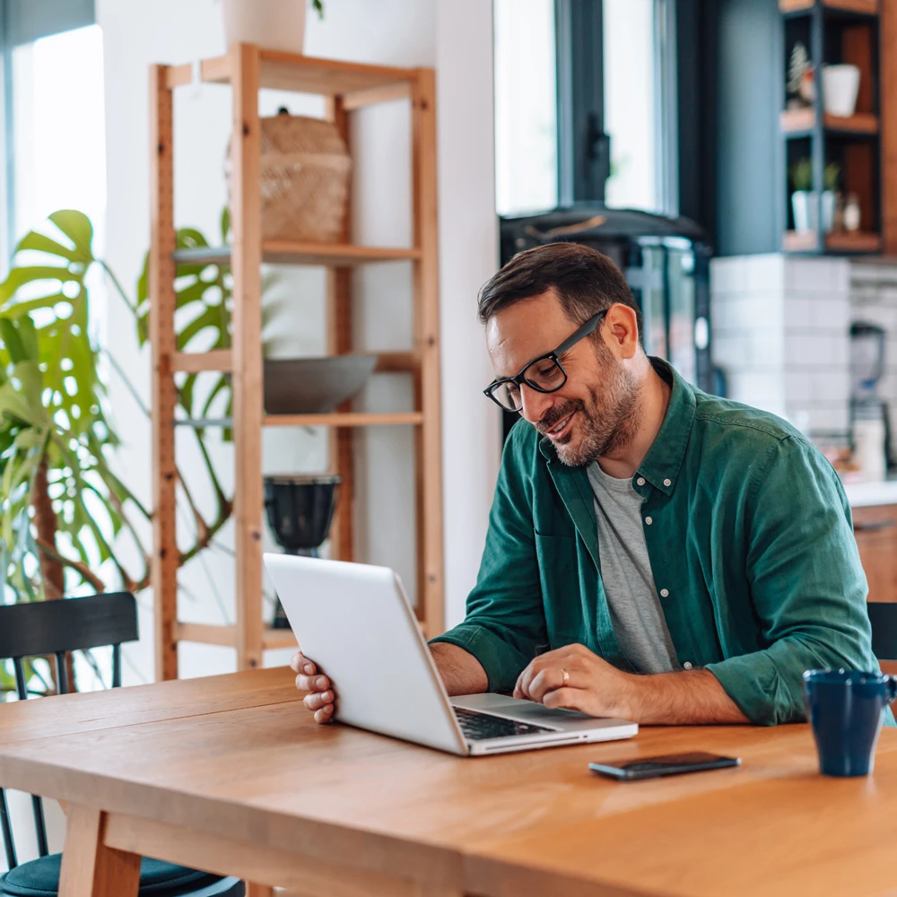 Man with glasses smiling looking at laptop