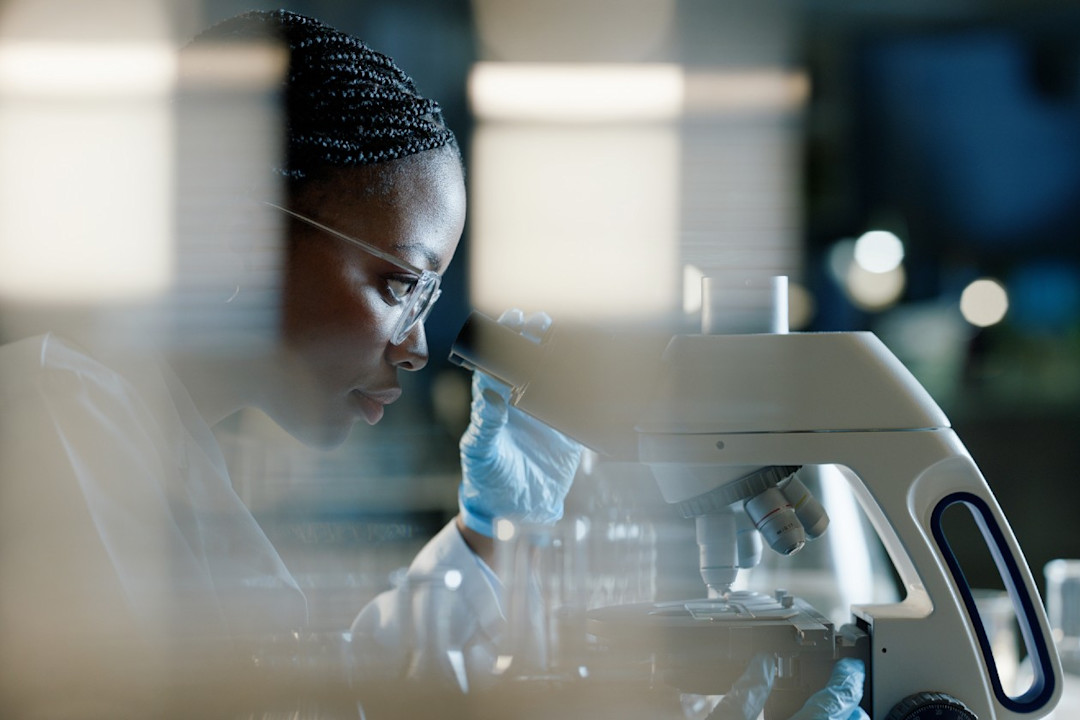 Female scientist using a microscope in a lab for drug development.jpg