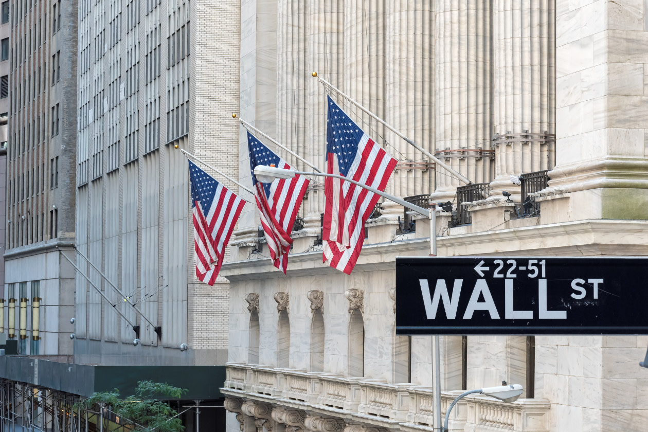 Wall street sign in New York City with New York Stock Exchange background.jpg