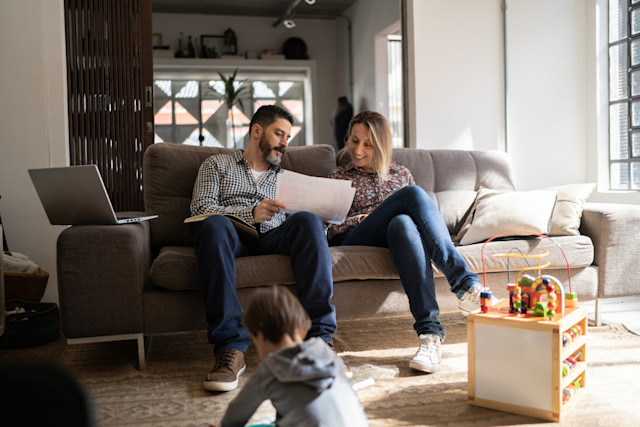 Parents working and son playing on the floor at home- GettyImages