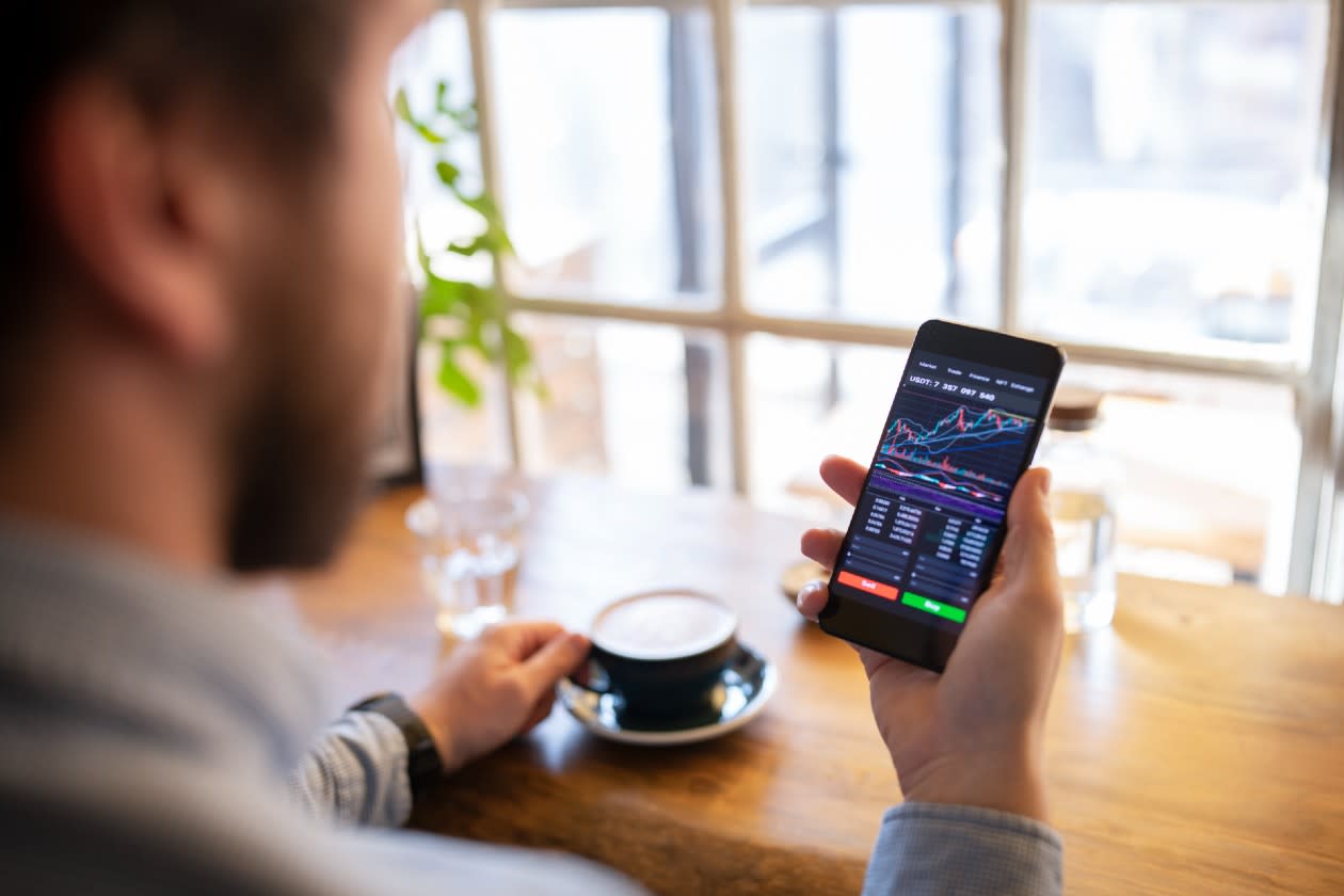 Man checking stock market information on his phone in a coffee shop.jpg