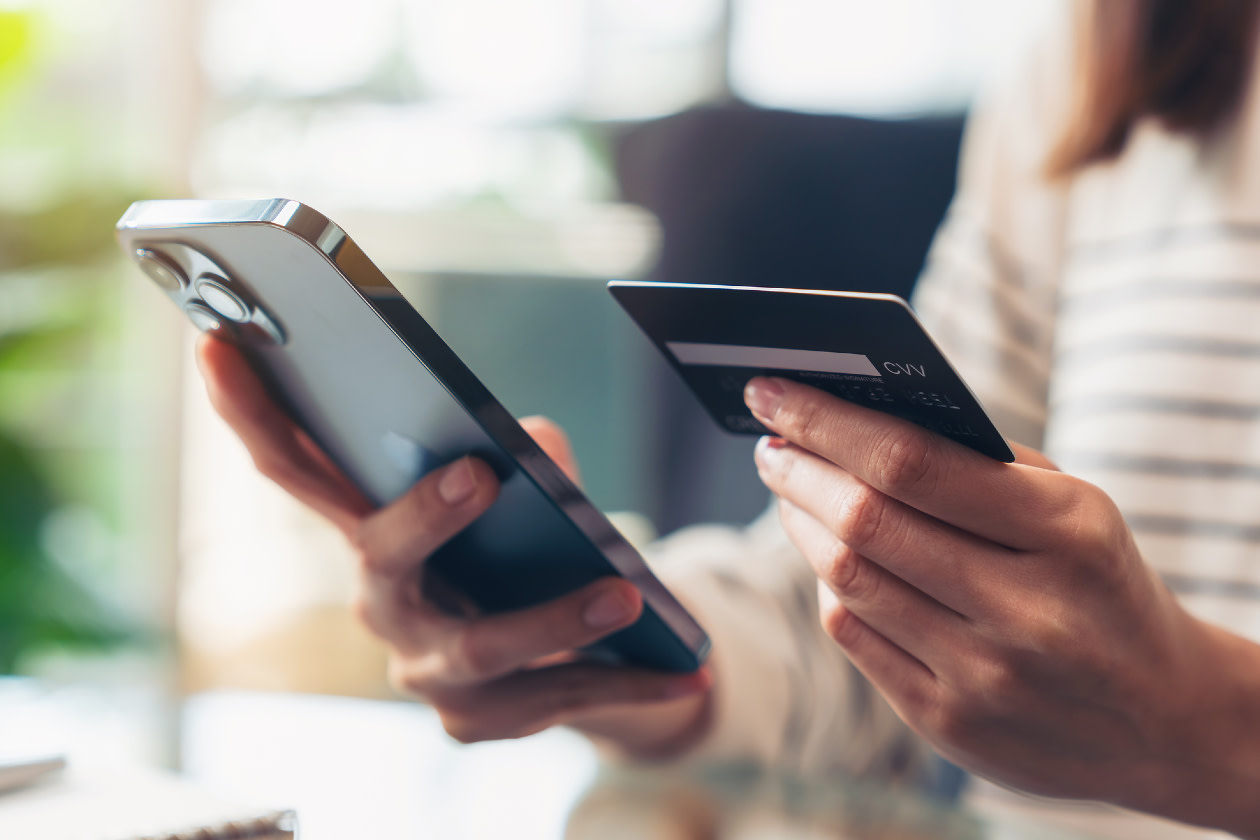 Woman hand holding credit cards and using smartphone- GettyImages