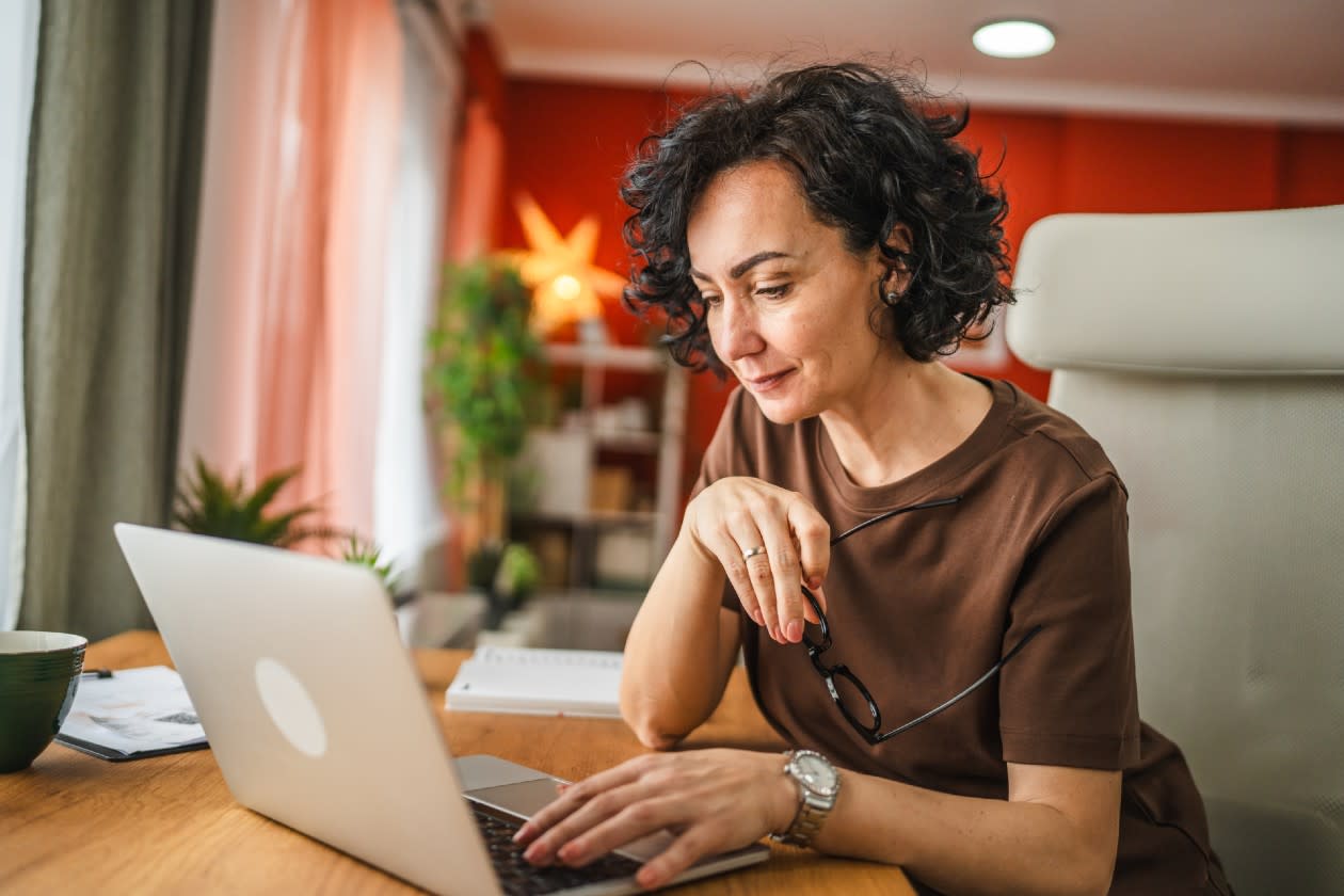 Woman looking content browsing on her laptop in living room.jpg