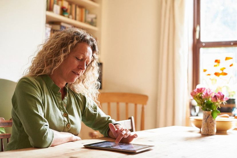 Woman doing research on her tablet in a sunny dining room