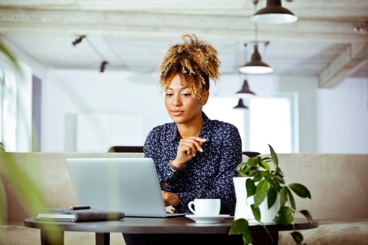 Smiling mid adult businesswoman using laptop in office.jpg