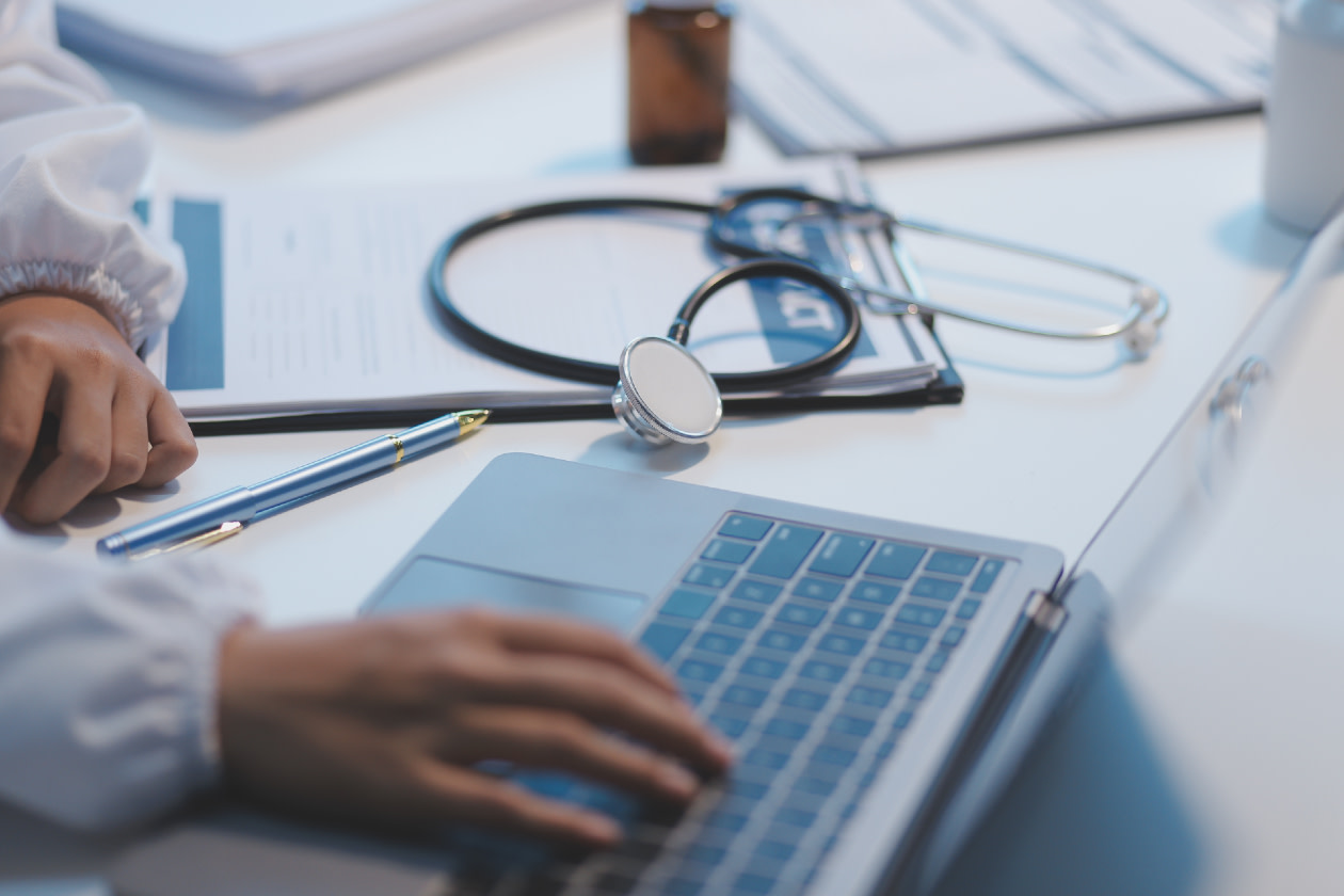 A professional doctor in scrubs working and reading medical research on her laptop at a hospital.jpg