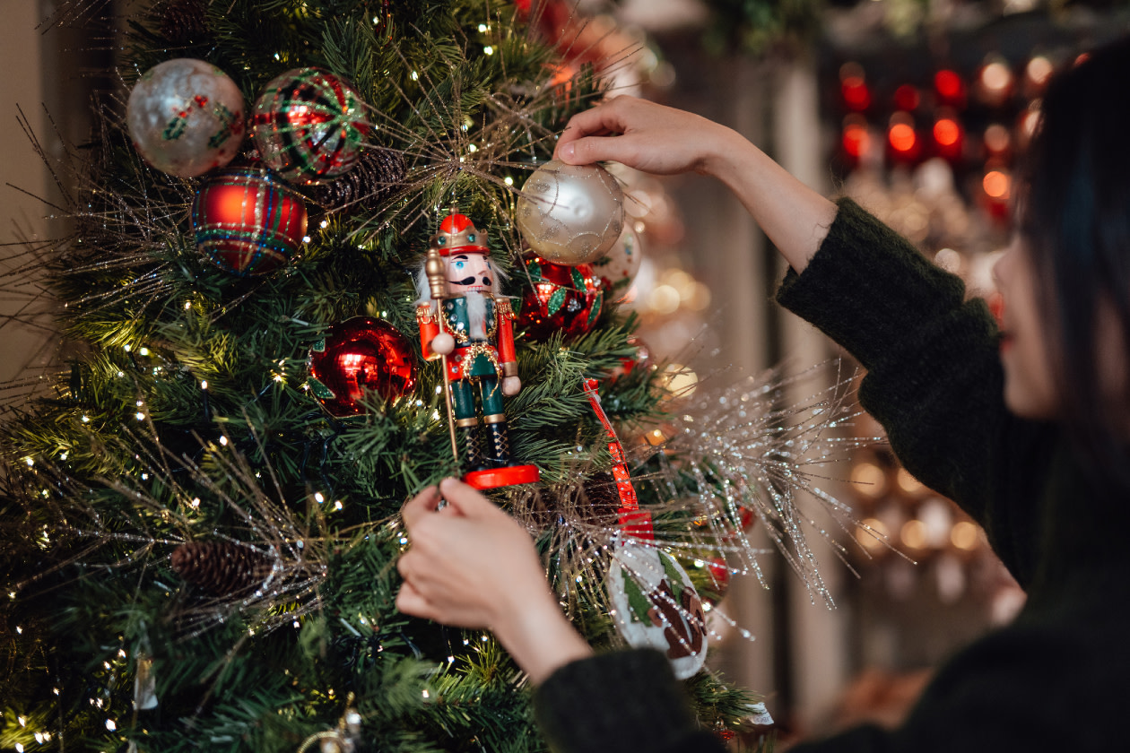 Young woman decorating Christmas tree with ornaments