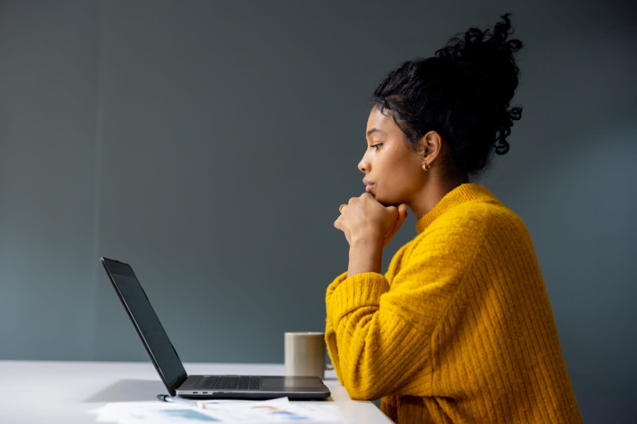 Woman in yellow jumper sat at kitchen table looking at laptop.jpg