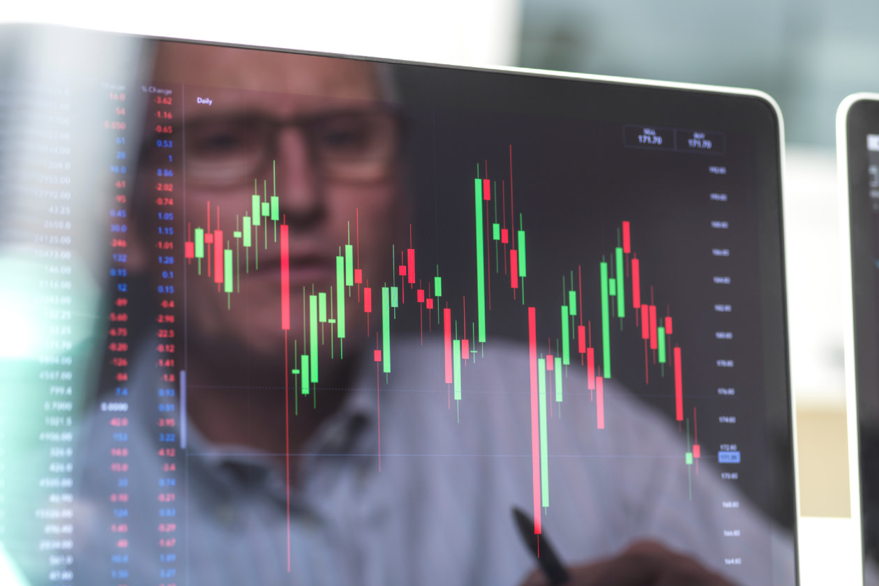Reflection of a stock trader viewing the performance of a company share price on screen