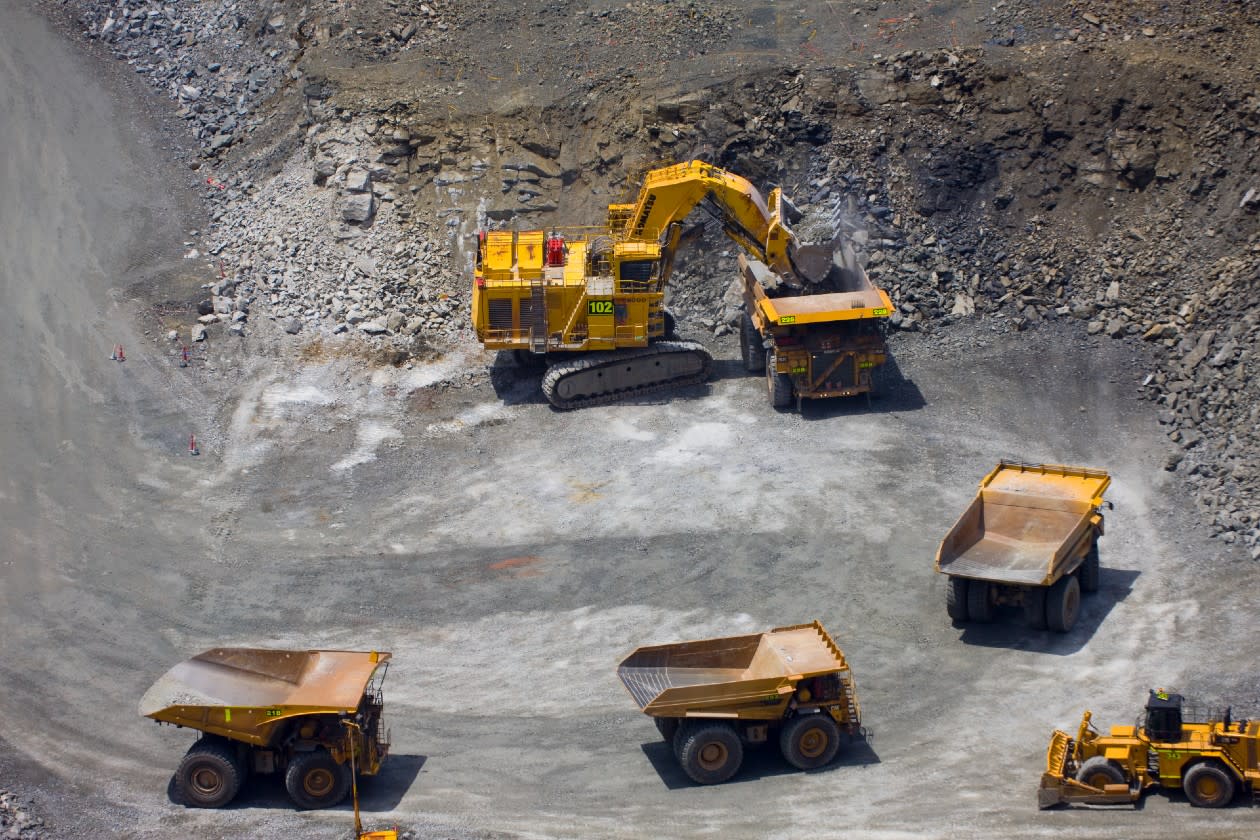 Barrick Gold - a digger and dump trucks at a gold mine.jpg