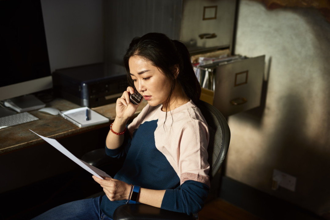 Lady on the phone looking at tax paperwork.jpg