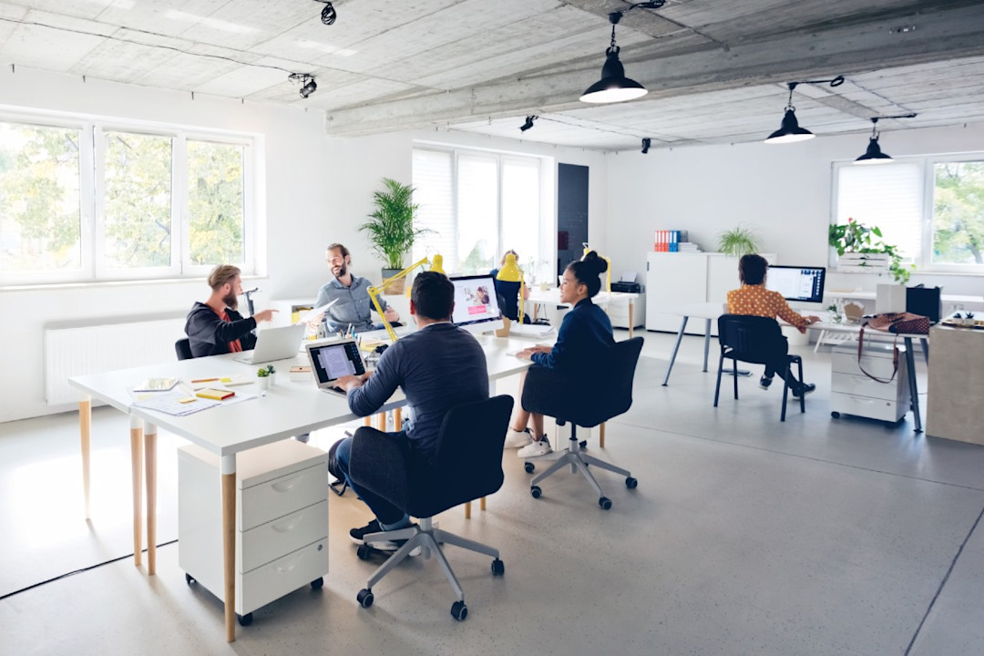 An open plan office of a small startup company with colleagues chatting.jpg