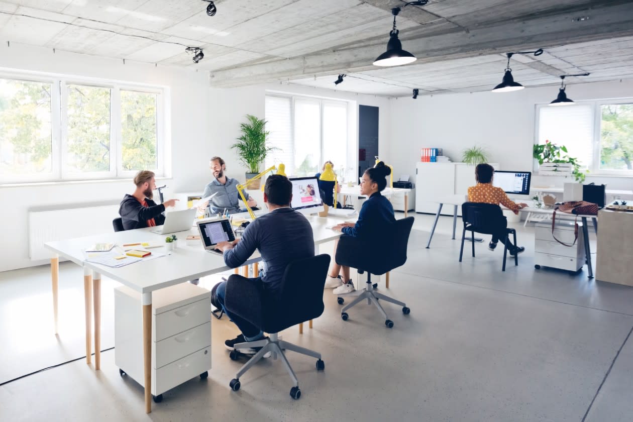 An open plan office of a small startup company with colleagues chatting.jpg