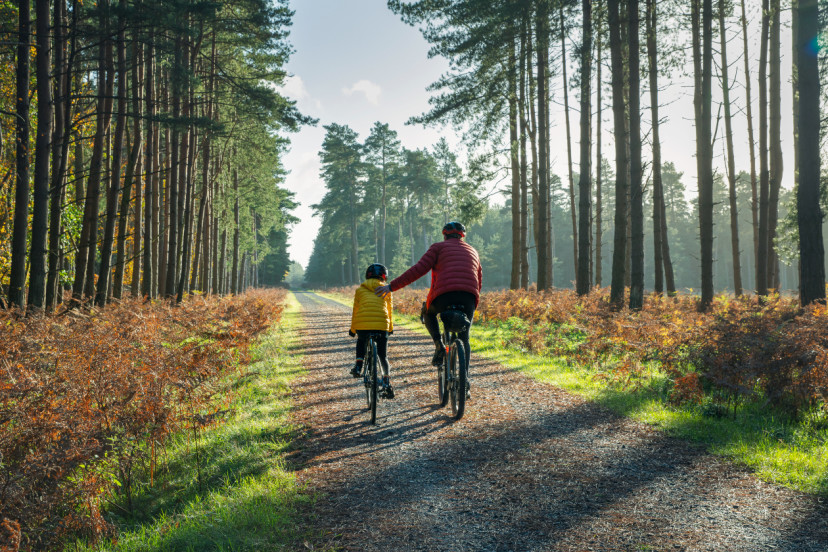 Young girl cycling with her father- GettyImages