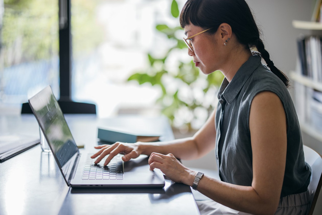 Woman concentrating on tasks on her laptop in a brightly lit space.jpg