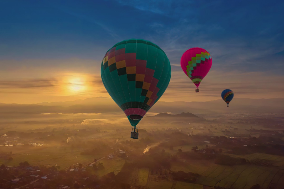 Three balloons trailing eachother along a sunset skyline.jpg