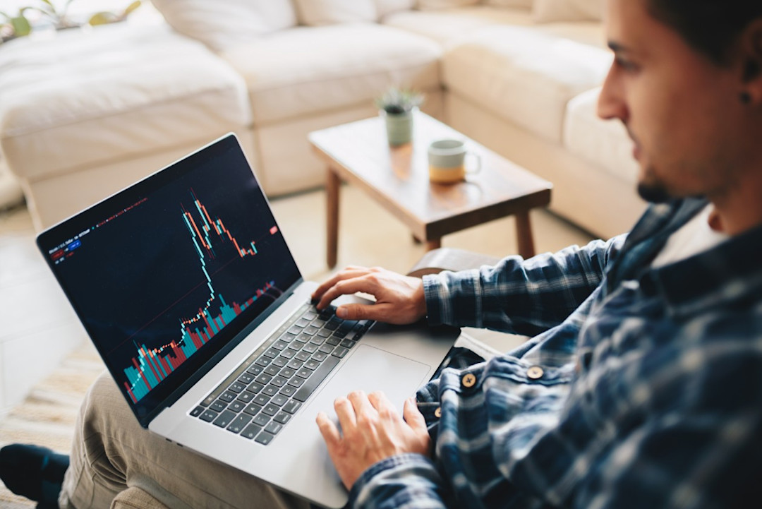 Man sitting relaxed in a chair viewing a chart on his laptop.jpg