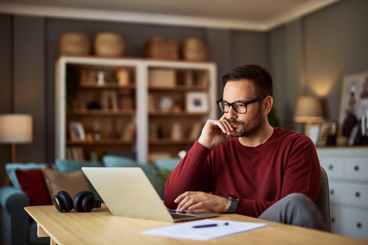 Man in red top looking at his investments on a laptop.jpg