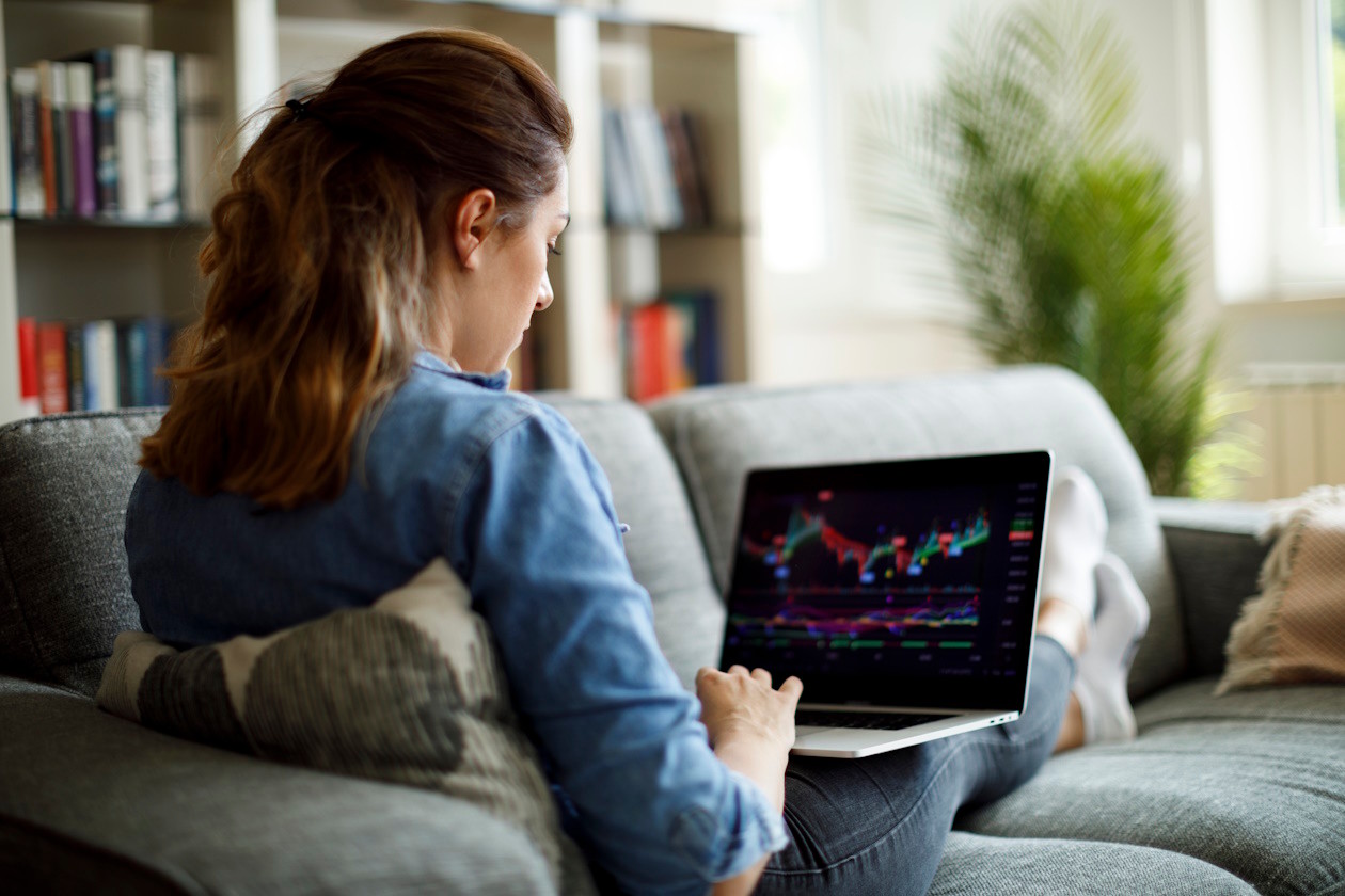 Woman sitting on sofa checking investment graph