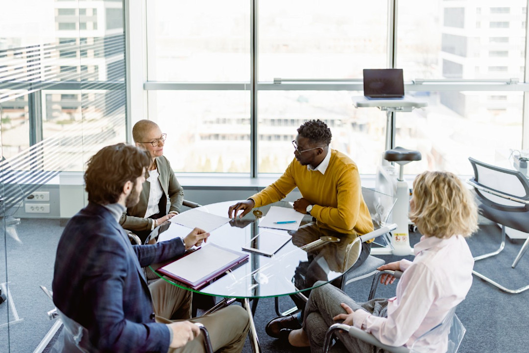 Group of employees discussing options around a table in a glass skyscraper office.jpg