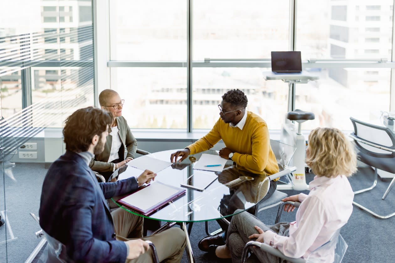 Group of employees discussing options around a table in a glass skyscraper office.jpg