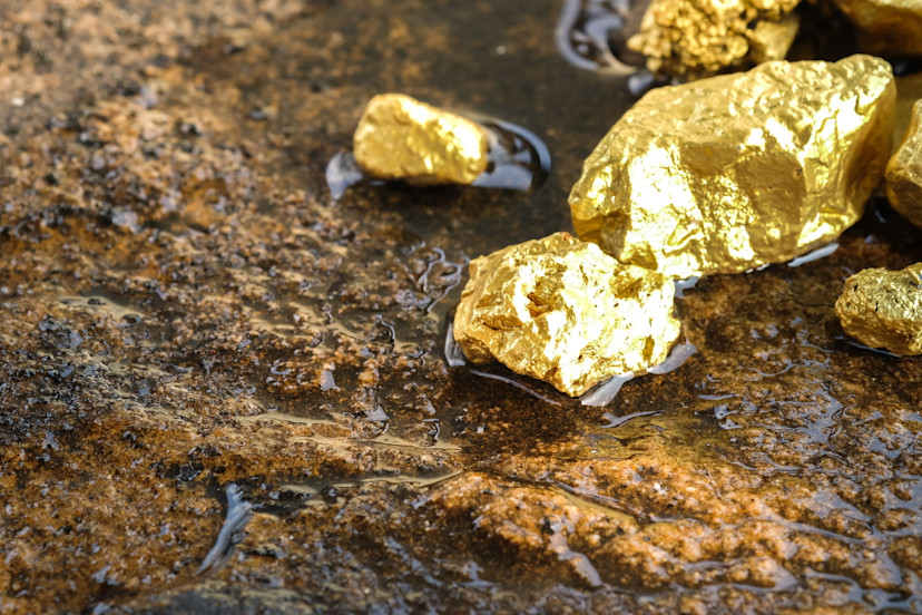 Gold nuggets sitting on a rock floor.jpg