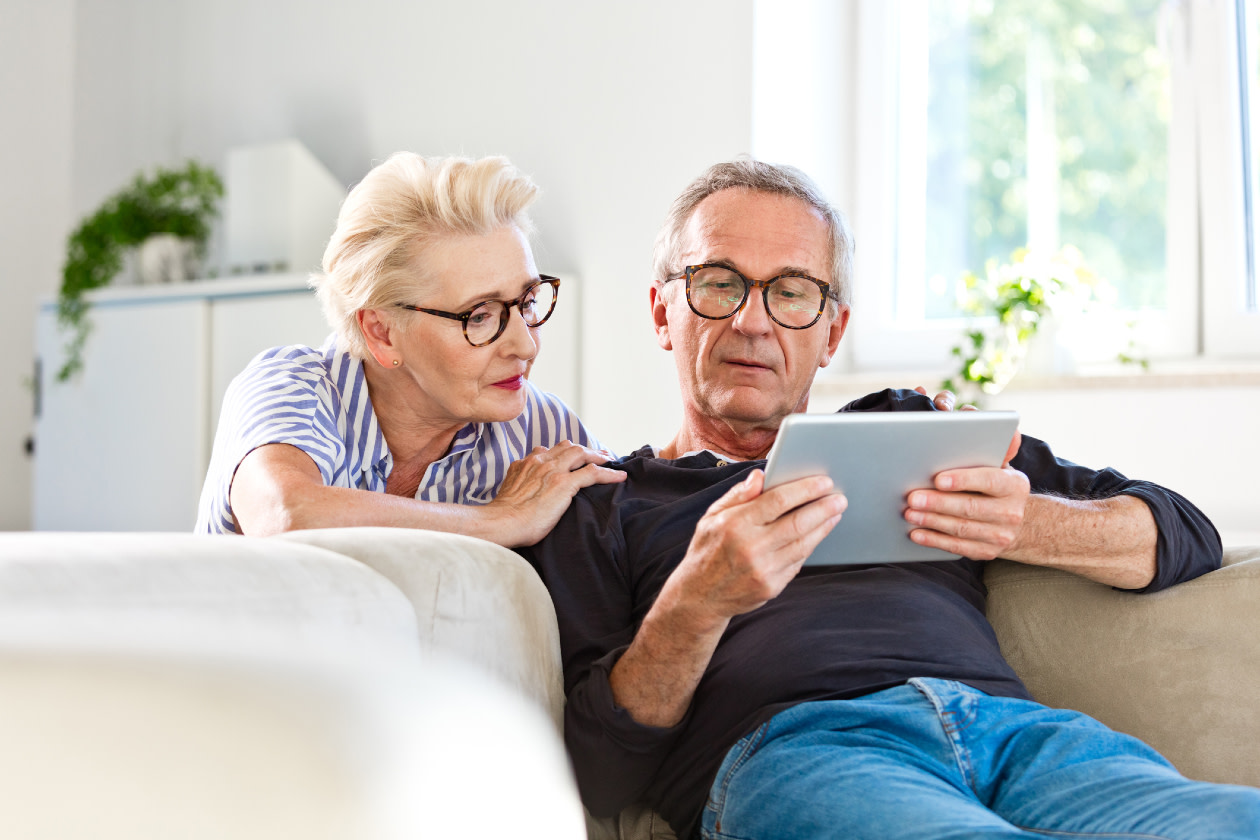 Senior couple watching digital tablet together at home- GettyImages