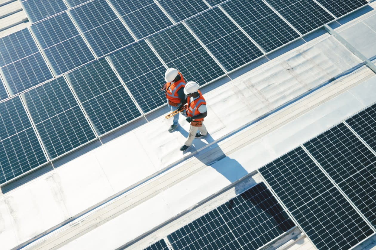 Two workers walking inbetween rows of solar panels.jpg