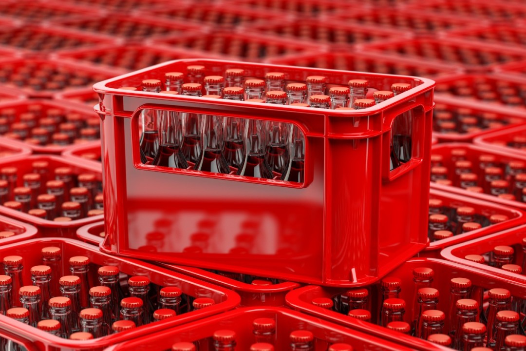 Coca-Cola bottles racked up in red crates in a factory.jpg