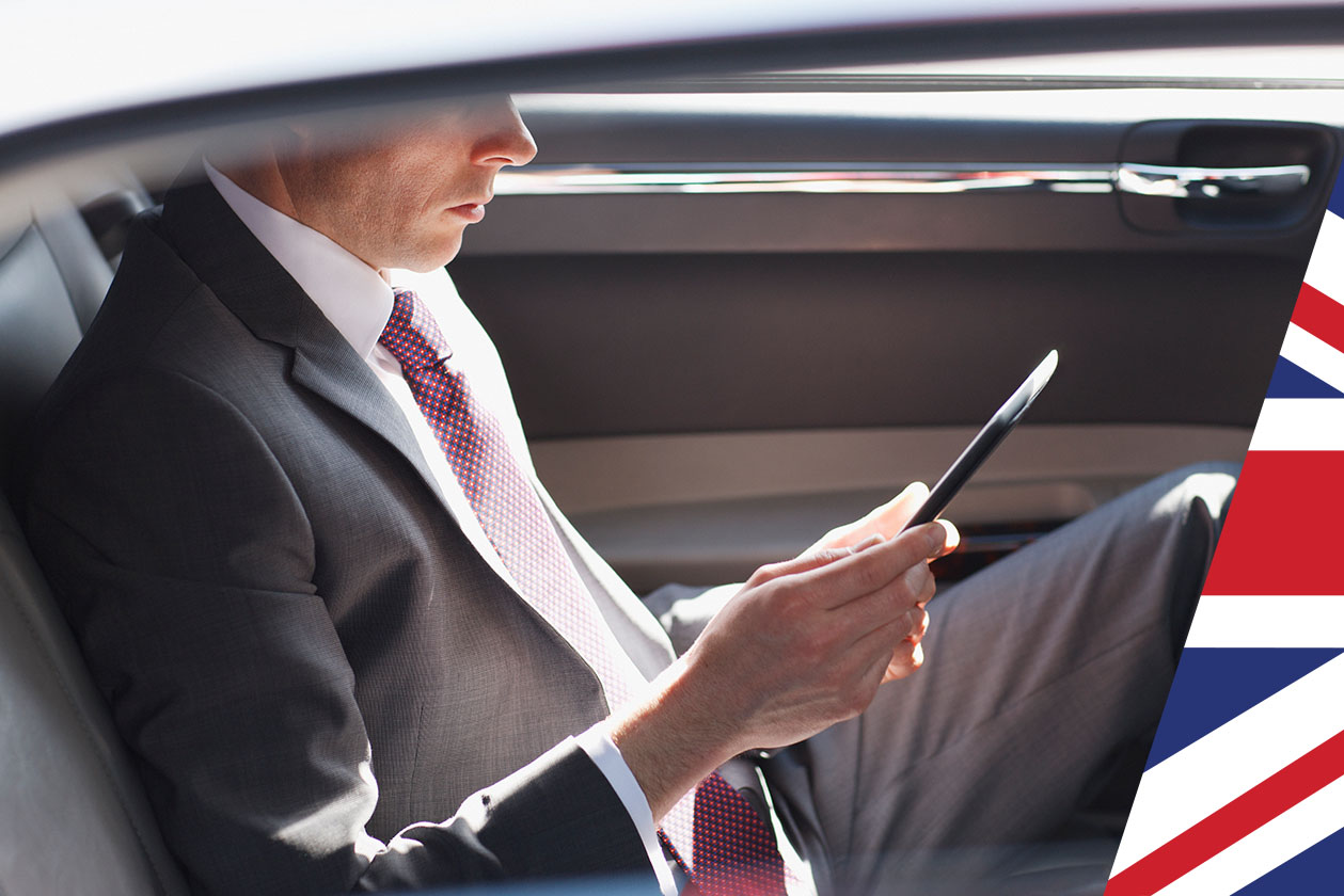 A man reading in backseat of car- Union jack overlay- GettyImages