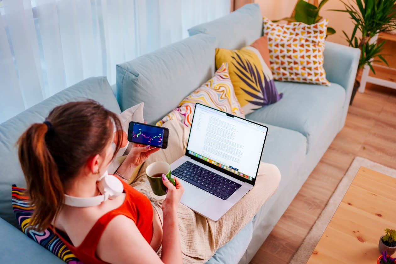 Young woman looking at a share price chart on her phone on the sofa.jpg
