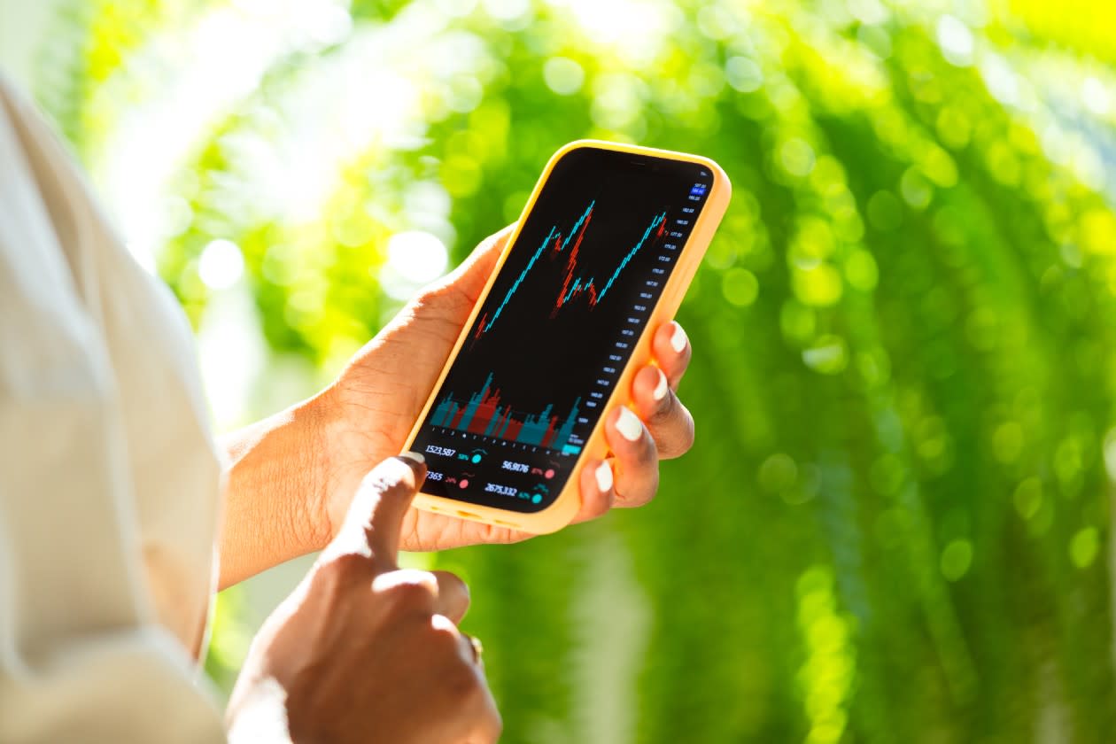 Woman reviewing investment peformance on her phone against a leafy summer background.jpg