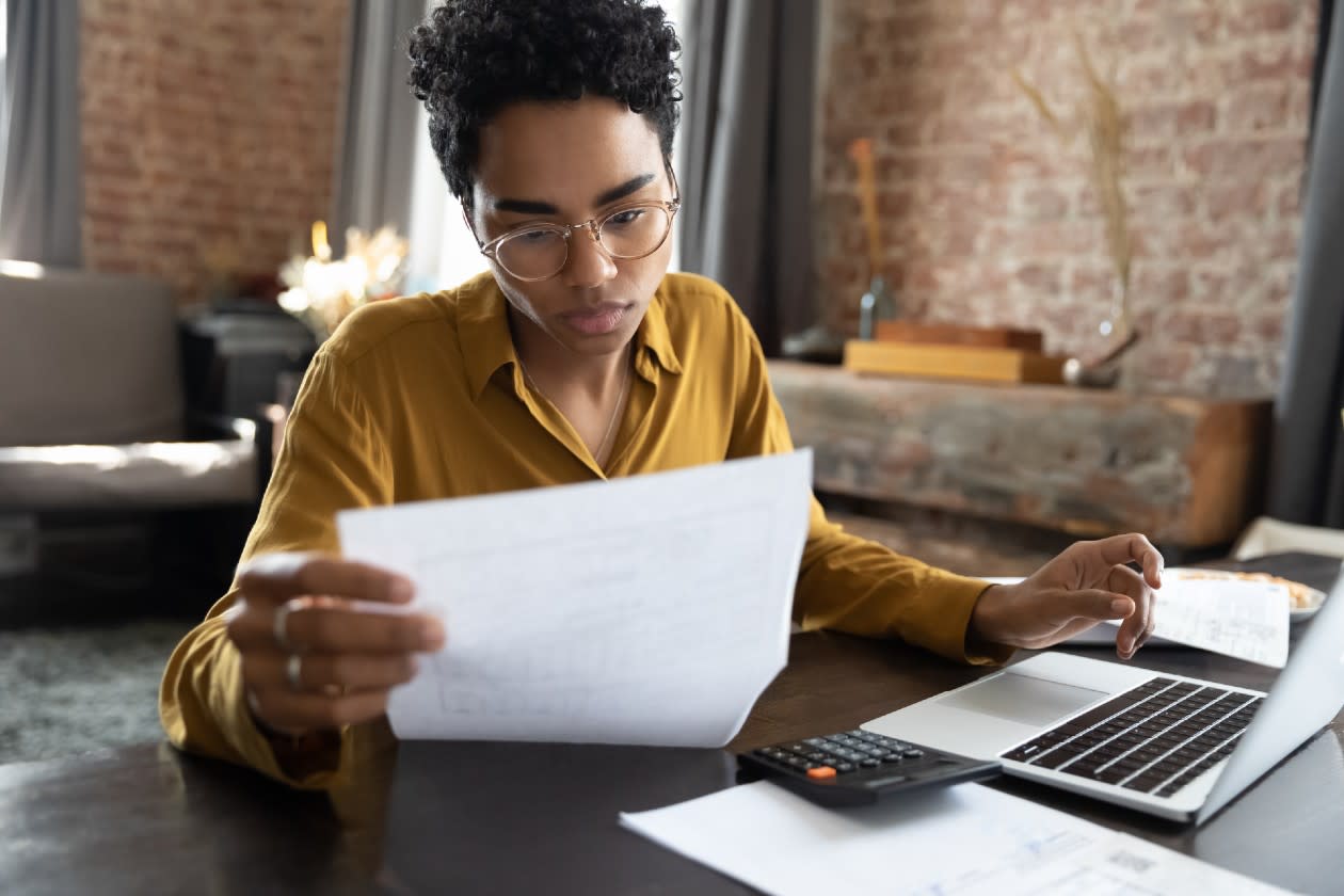 Woman inspecting a letter while doing taxes on her laptop.jpg