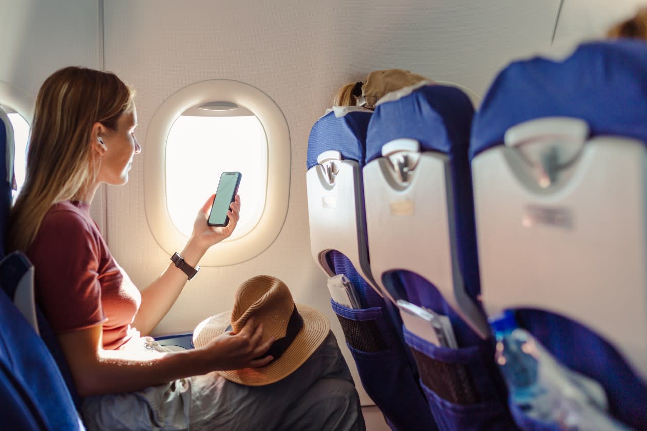 Woman reading phone next to window on a commercial flight.jpg